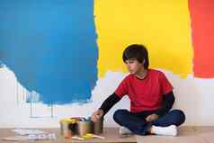 年轻的男孩画家休息绘画墙