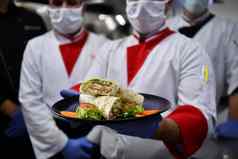 集团厨师站厨房餐厅穿保护医疗面具手套冠状病毒正常的概念