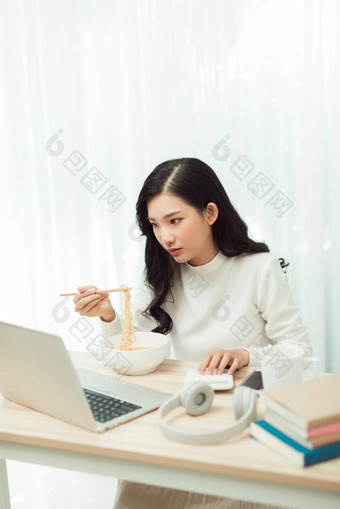 肖像年轻的亚洲女人自由职业者工作移动PC首页<strong>吃</strong>亚洲食物<strong>外卖</strong>