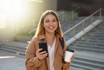 微笑年轻的业务女人持有智能手机<strong>咖啡</strong>早....模糊楼梯背景