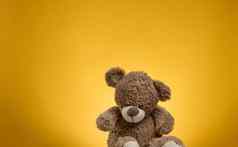 可爱的棕色（的）泰迪熊补丁坐在黄色的背景儿童玩具
