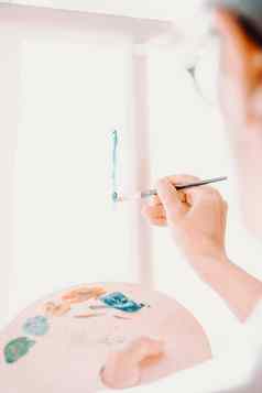 特写镜头女高级艺术家手持有油漆刷画绘画蓝色的油漆色彩斑斓的情感石油绘画当代画家创建现代摘要一块细艺术
