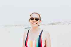 年轻的女人泳衣太阳镜微笑相机阳光明媚的一天海滩自由假期概念肖像