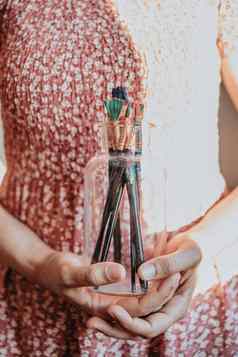 年轻的女人艺术家手抓住瓶填满油漆铅笔刷准备好了绘画丙烯酸艺术概念艺术家概念美衣服概念古董太阳豆