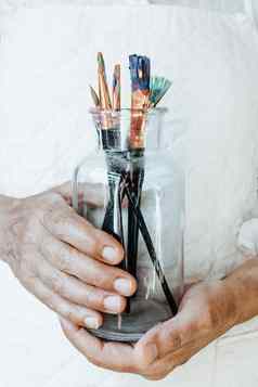 手抓住瓶填满油漆铅笔刷准备好了绘画丙烯酸艺术概念艺术家概念