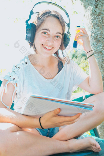 年轻的女人坐着花园微笑研究大学<strong>享受</strong>户外娱乐听力音乐移动PC复制空间<strong>人生</strong>活方式概念打字电脑