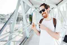 肖像年轻的男人。机场公共汽车站行李袋手提箱持有地图微笑赶时髦的人旅行者太阳镜复制空间阳光明媚的一天