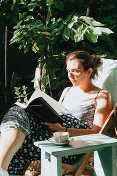 女人阅读书下弯的椅子阳光明媚的一天复制空间放松爱好概念社会网络
