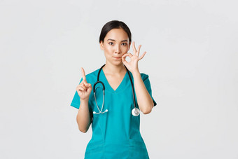 科维德医疗保健工人流感大流行概念严肃的表情担心亚洲女护士医生秘密摇晃手指显示口密封压缩嘴唇手势