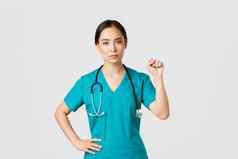 科维德医疗保健工人流感大流行概念严肃的表情自信亚洲女医生显示支持研究员同事冠状病毒提高拳头团结手势