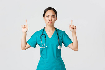 科维德医疗保健工人流感大流行概念悲观的失望亚洲女医生医生实习医生风云指出手指扮鬼脸不高兴站白色背景