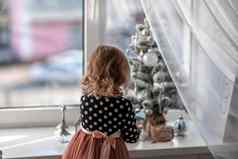 女孩坐着床上窗口装修小树小圣诞节玩具快乐健康的孩子庆祝传统的家庭假期可爱的婴儿