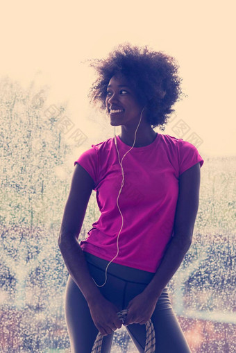 肖像年轻的非洲式发型美国女人健身房听音乐