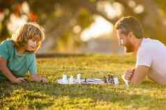 父亲儿子玩国际象棋早....公园父亲一天快乐家庭为人父母