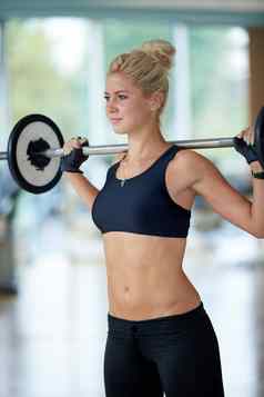 年轻的女人健身健身房提升权重