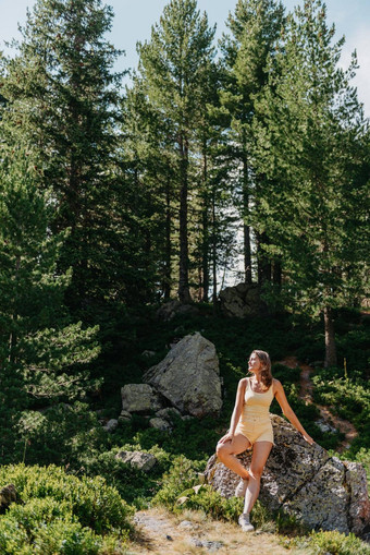 年轻的女人旅游坐着山峰美丽的山景观运动女孩绿色森林山天空湖旅行旅游赶时髦的人女孩山时尚的女人网纹衬衫坐着石头森林旅游热概念徒步旅行旅行夏天神秘的木美丽的自然