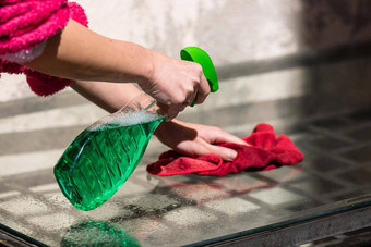 女人清洁玻璃表格红色的超细纤维地毯清洁喷雾器清洁服务概念做家务管家概念