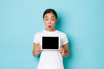 兴奋惊讶美丽的亚洲女白色t恤数字平板电脑屏幕惊讶激动显示图表演示在线购物网站光蓝色的背景