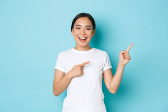 美丽的快乐亚洲女孩白色t恤帮助选择显示展示横幅朝鲜文女人热情的指出上角落里蓝色的背景