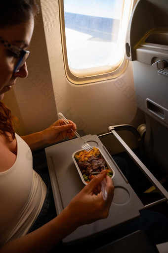 高加索人女人飞行经济类吃午餐托盘表格董事会飞机