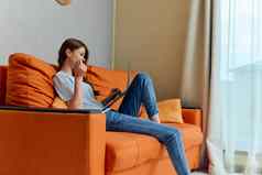快乐的女人聊天橙色沙发上移动PC技术