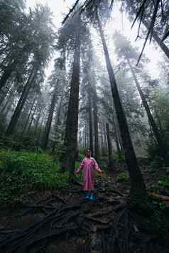 年轻的女人雨衣走森林雨