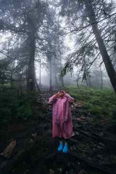 年轻的女人雨衣走森林雨