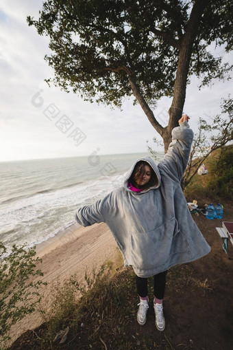 年轻的女人冷秋天海滨摆姿势相机