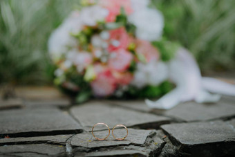 婚礼黄金环新娘花束花石头背景白色粉红色的婚礼花束玫瑰一对婚礼环