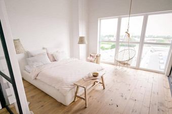 大明亮的卧室极简主义风格柔和的奶油颜色双床上白色墙柳条洗衣篮子柳条吊灯米色床上板凳上大窗口放荡不羁的挂椅子木地板上