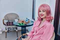 女人粉红色的头发坐着古董咖啡馆扶手椅放松