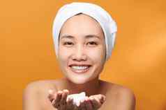 快乐的亚洲女持有发泡清洁剂清洁新鲜的健康的皮肤