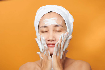 关闭美丽的年轻的亚洲女人清洗泡沫皮肤护理