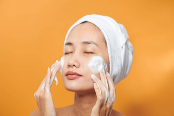 温柔的半裸的女人包装毛巾洗脸发泡清洁剂孤立的橙色背景