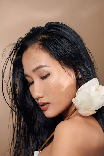 美丽的年轻的亚洲女孩自然化妆湿头发摆姿势工作室米色背景