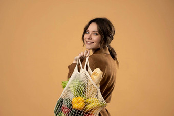 年轻的女人持有网杂货店袋蔬菜概念塑料浪费塑料免费的生态友好的概念可持续发展的生活方式