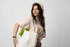 女人持有纺织杂货店袋蔬菜浪费概念package-free食物购物生态友好的自然袋有机水果蔬菜
