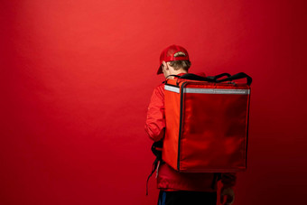 年轻的快递红色的统一的t恤红色的食物热袋肩膀站孤立的红色的背景工作室食物交付服务