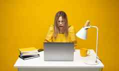 年轻的愤怒的困惑秘书员工业务女人传播手黄色的衬衫坐工作白色办公室桌子上移动PC电脑孤立的黄色的背景
