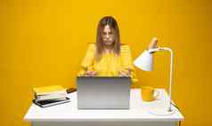 年轻的愤怒的困惑秘书员工业务女人传播手黄色的衬衫坐工作白色办公室桌子上移动PC电脑孤立的黄色的背景