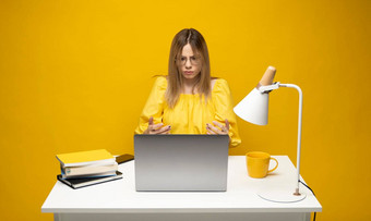 年轻的愤怒的困惑秘书<strong>员工</strong>业务女人传播手黄色的衬衫坐工作白色办公室桌子上移动PC电脑孤立的黄色的<strong>背景</strong>