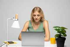 微笑业务女人工作移动PC孤立的灰色背景肖像漂亮的年轻的女人研究坐着表格灰色移动PC电脑笔记本