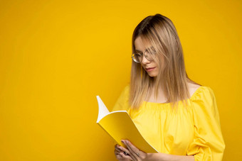 肖像年轻的学生女人黄色的t恤眼镜<strong>阅读</strong>书孤立的黄色的背景女孩<strong>阅读</strong>研究