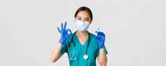 科维德冠状病毒疾病医疗保健工人概念可爱的亚洲女医生医生医疗面具橡胶手套显示手势持有注射器疫苗白色背景