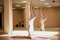 年轻的运动女人健身教练粉红色的运动服装伸展运动普拉提瑜伽席工作室镜子女健身瑜伽例程概念健康的生活方式和谐