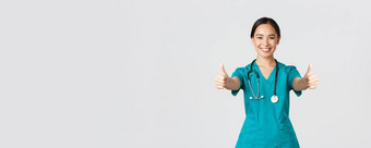 科维德医疗保健工人流感大流行概念微笑漂亮的亚洲女医生护士实习医生风云确保好显示竖起大拇指批准同意白色背景