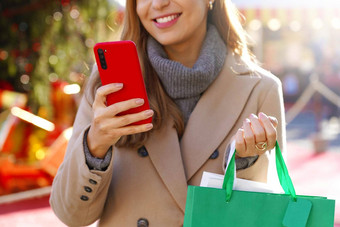 美丽的女人持有智能<strong>手机</strong>购物在线携带袋圣诞<strong>节</strong>时间裁剪图片焦点手电话