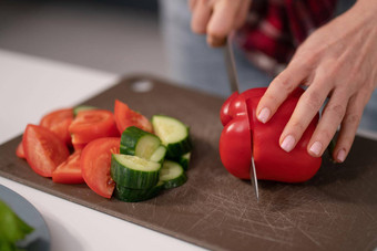 切割片新鲜的蔬菜沙拉年轻的家庭主妇减少甜蜜的胡椒黄瓜番茄董事会准备家庭晚餐站厨房健康的食物生活健康的生活方式