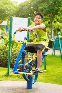 快乐亚洲体育运动男孩玩摇摆不定的操场上花园