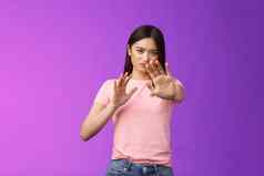 不高兴强烈的不情愿的亚洲女孩阻塞保护脸提高手停止禁止手势皱着眉头生闷气的拒绝困扰提供站紫色的背景拒绝